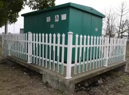 Outdoor pad-mounted transformer enclosure installed on a concrete pad with a protective fence for environmental exposure review