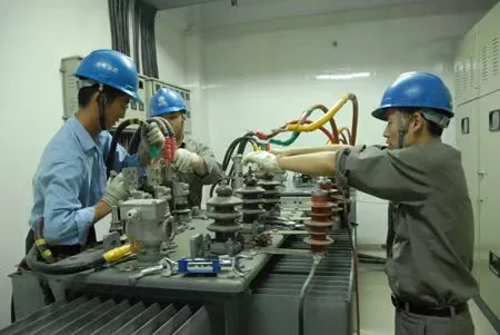 Technicians inspecting oil-immersed transformer bushings and top cover during maintenance